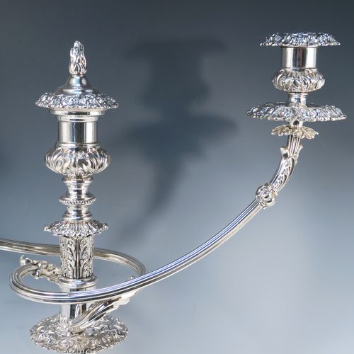 A large, bold, and very handsome pair of Antique Georgian Sterling Silver and Old Sheffield plated candelabra, having round baluster bodies with applied Regency style applied floral and scroll decoration, with removable three lights arms, original removable nozzles, drip pans, and flame extinguishers. The candelabra bases were made in Sterling Silver by Smith, Tate, Houle and Tate of Sheffield in 1822, whilst the original branches are made from Old Sheffield plate, which is quite a common combination from this period. The dimensions of this fine hand-made pair of antique silver candelabra are height 56 cms (22 inches), and spread across arms 43 cms (17 inches).