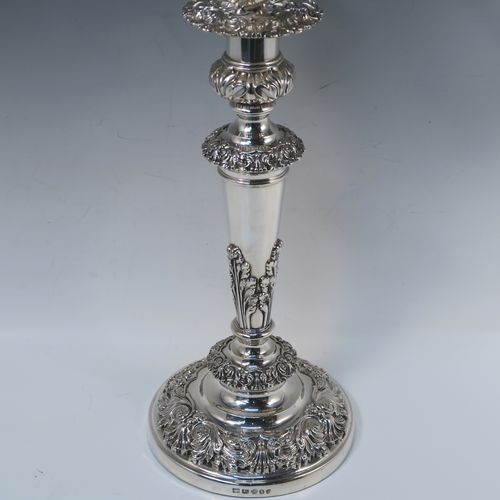 A large, bold, and very handsome pair of Antique Georgian Sterling Silver and Old Sheffield plated candelabra, having round baluster bodies with applied Regency style applied floral and scroll decoration, with removable three lights arms, original removable nozzles, drip pans, and flame extinguishers. The candelabra bases were made in Sterling Silver by Smith, Tate, Houle and Tate of Sheffield in 1822, whilst the original branches are made from Old Sheffield plate, which is quite a common combination from this period. The dimensions of this fine hand-made pair of antique silver candelabra are height 56 cms (22 inches), and spread across arms 43 cms (17 inches).