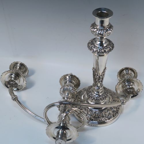 A large, bold, and very handsome pair of Antique Georgian Sterling Silver and Old Sheffield plated candelabra, having round baluster bodies with applied Regency style applied floral and scroll decoration, with removable three lights arms, original removable nozzles, drip pans, and flame extinguishers. The candelabra bases were made in Sterling Silver by Smith, Tate, Houle and Tate of Sheffield in 1822, whilst the original branches are made from Old Sheffield plate, which is quite a common combination from this period. The dimensions of this fine hand-made pair of antique silver candelabra are height 56 cms (22 inches), and spread across arms 43 cms (17 inches).