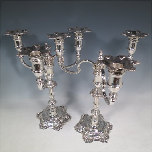A Sterling Silver cast pair of George II style three-light candelabra, having round baluster bodies with six-shell borders, removable scroll arms with nozzles, and a central finial. Made by Mappin & Webb of Birmingham in 1969. The dimensions of this fine hand-made pair of silver candelabra are height 30 cms (11.75 inches), spread across arms 25 cms (9.75 inches), and with a total weight of approx. 2,538g (82 troy ounces). Please note that these candelabra are all cast and not filled.