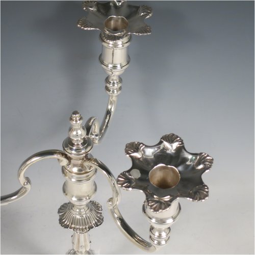 A Sterling Silver cast pair of George II style three-light candelabra, having round baluster bodies with six-shell borders, removable scroll arms with nozzles, and a central finial. Made by Mappin & Webb of Birmingham in 1969. The dimensions of this fine hand-made pair of silver candelabra are height 30 cms (11.75 inches), spread across arms 25 cms (9.75 inches), and with a total weight of approx. 2,538g (82 troy ounces). Please note that these candelabra are all cast and not filled.