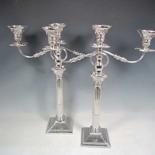 A Sterling silver pair of candelabra in the Corinthian style, having removable arms with three lights, fluted columns with stepped square bases, double swirl reeded arms, acanthus leaf capitals, removable nozzles with drip pans, and bead-edged borders. Made in London in 1933. The dimensions of this fine hand-made silver pair of candelabra are height 49 cms (19.25 inches), and spread across arms 40 cms (15.75 inches).   