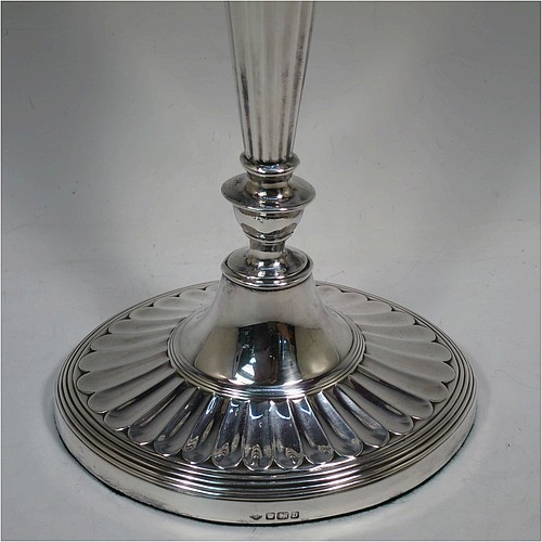 A very pretty pair of Antique Sterling Silver candelabra in a Neoclassical style, having removable arms with three lights, fluted columns with oval bases, double swirl and reeded arms, capitals with fluted and reeded decoration, removable nozzles with drip pans and a central flame extinguisher, and reed-edged borders. Made by William Hutton and Sons of Sheffield in 1913. The dimensions of this fine hand-made pair of antique silver candelabra are height 43 cms (17 inches), and spread across arms 34 cms (13.3 inches).