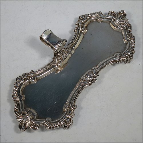 An Antique Georgian Old Sheffield Plated candle scissor snuffer stand and candle scissor snuffer, the stand having an applied floral & scroll border with a cast scroll handle and sitting on four cast scroll feet, the scissor snuffer with matching decoration and all in original working condition. Made in ca. 1820. The dimensions of this fine hand-made antique Old Sheffield Plated snuffer stand and scissors are length 24 cms (9.5 inches), height (inc. handle) 5 cms (2 inches), and width (inc. handle) 11 cms (4.25 inches),