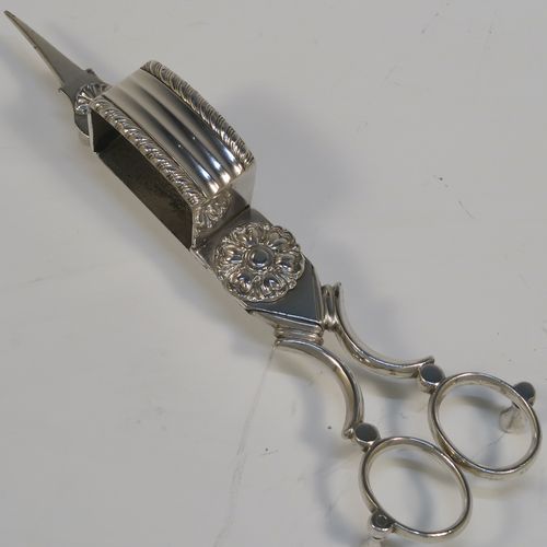 A very handsome Antique Georgian Old Sheffield Plated candle scissor snuffer stand and candle scissor snuffer, the stand having an applied floral & gadroon border, a plain undecorated ground, and sitting on a flat base with four stud feet and original tin backing . The scissor snuffer with matching decoration and all in original working condition. This beautiful antique Old Sheffield plated candle scissor snuffer and stand was made in ca. 1810. The dimensions of this fine hand-made antique Old Sheffield Plated snuffer stand and scissors are length 23 cms (9 inches), and width 10 cms (4 inches),