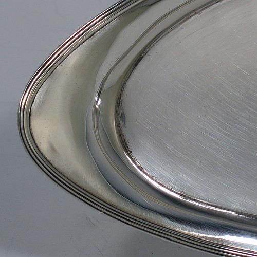 A handsome Antique Georgian Sterling Silver candle scissor snuffer stand or tray, having a plain elongated oval-shaped body with a central vacant cartouche surrounded by hand-engraved scroll-work and laurel leaves, an applied reeded border, and sitting on a flat base. Made by Soloman Hougham of London in 1800. The dimensions of this fine hand-made antique silver snuffer tray or stand are length 24 cms (9.5 inches), width 10.5 cms (4.25 inches), and it weighs approx. 127g (4 troy ounces).
