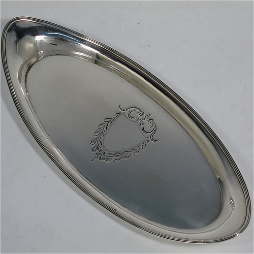 A handsome Antique Georgian Sterling Silver candle scissor snuffer stand or tray, having a plain elongated oval-shaped body with a central vacant cartouche surrounded by hand-engraved scroll-work and laurel leaves, an applied reeded border, and sitting on a flat base. Made by Soloman Hougham of London in 1800. The dimensions of this fine hand-made antique silver snuffer tray or stand are length 24 cms (9.5 inches), width 10.5 cms (4.25 inches), and it weighs approx. 127g (4 troy ounces).