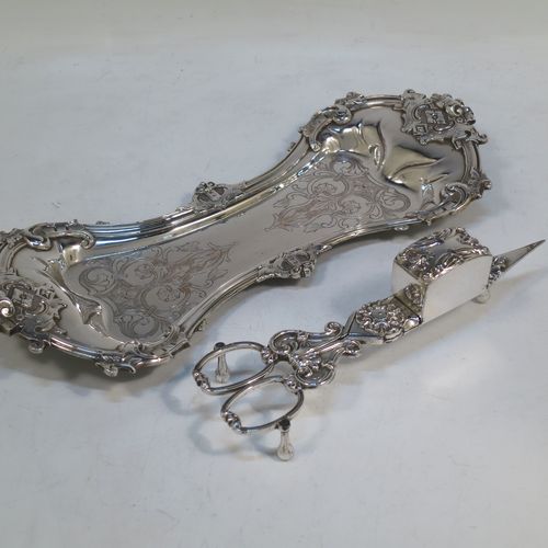 An Antique Georgian Old Sheffield Plated candle scissor snuffer stand and candle scissor snuffer, the stand having an applied floral & scroll border, a hand-chased ground with floral decoration, and sitting on a flat base with four stud feet. The scissor snuffer with matching decoration and all in original working condition. Made in ca. 1830. The dimensions of this fine hand-made antique Old Sheffield Plated snuffer stand and scissors are length 26 cms (10.25 inches), and width 11 cms (4.25 inches),  