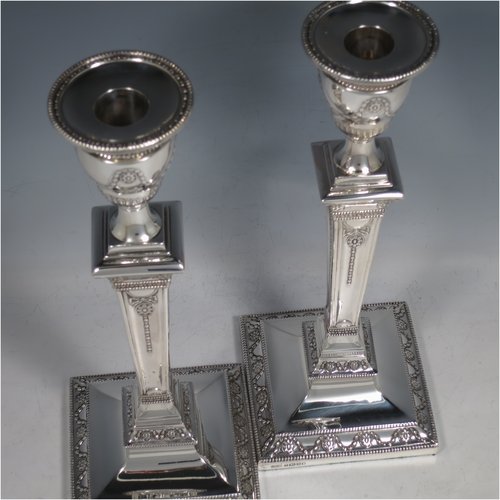 An Antique Victorian Sterling Silver pair of large table candlesticks, in a Neoclassical style, having square cross-section bodies with hand-chased swags and garland decoration, tapering columns, removable nozzles, and bead-edged borders. Made by J. K. Bembridge of Sheffield in 1886. The dimensions of these fine hand-made silver candlesticks are height 28 cms (11 inches), and 11 cms (4.25 inches) square at bases.   
