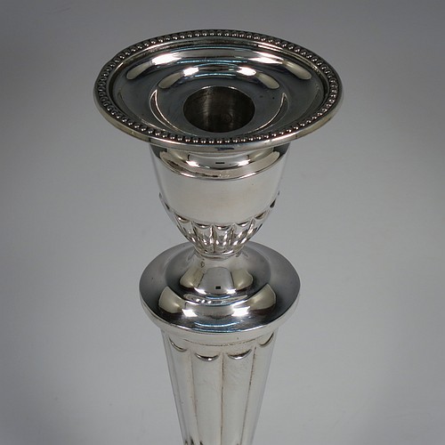 A Sterling Silver very pretty pair of large table candlesticks, in a neoclassical Adams style, having oval bodies with tapering columns and hand-chased inverted flute decoration, with applied bead-edged borders, and removable nozzles. Made by D. J. Silver of London in 1963. The dimensions of these fine hand-made silver candlesticks are height 29 cms (11.5 inches), and length at bases 15 cms (6 inches).