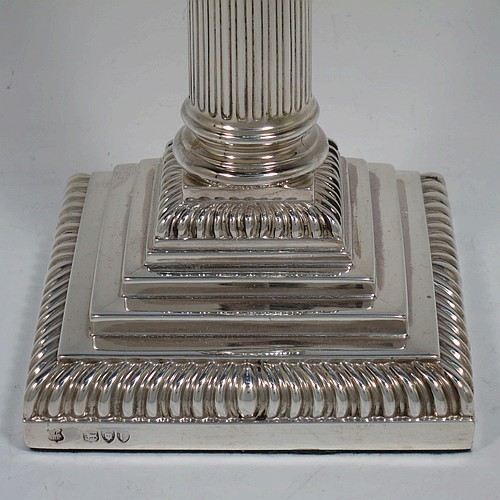 A very handsome and bold pair of Antique Victorian Sterling Silver table candlesticks, in a Neoclassical Corinthian style having square stepped bases, fluted columns, acanthus leaf capitals, removable nozzles, and gadroon borders. Made by Gibson and Langland of London in 1895. The dimensions of this fine hand-made pair of antique silver candlesticks are height 28 cms (11 inches), and their bases are 11.5 cms (4.5 inches) square.
