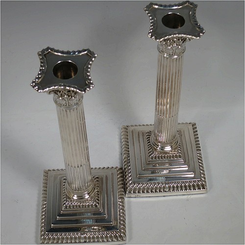 A very handsome and bold pair of Antique Victorian Sterling Silver table candlesticks, in a Neoclassical Corinthian style having square stepped bases, fluted columns, acanthus leaf capitals, removable nozzles, and gadroon borders. Made by Gibson and Langland of London in 1895. The dimensions of this fine hand-made pair of antique silver candlesticks are height 28 cms (11 inches), and their bases are 11.5 cms (4.5 inches) square.