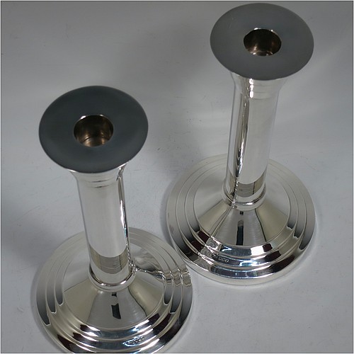 A very unusual and handsome Sterling Silver pair of Art Deco style candlesticks, having round stepped bases, plain round straight-sided columns, with stepped capitals and removable nozzles. Made by Walker and Hall of Sheffield in 1955. The dimensions of these fine hand-made Art Deco style silver table candlesticks are height 21 cms (8.25 inches), and diameter at base 12 cms (4.75 inches).