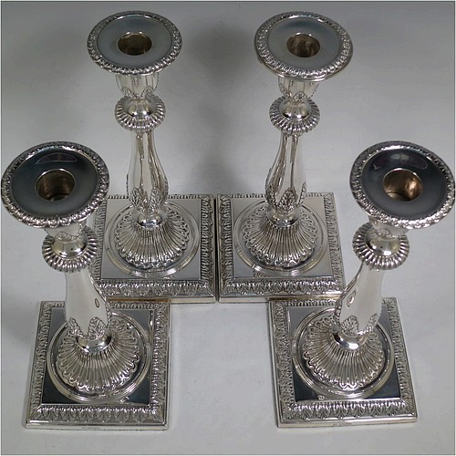 A very pretty set of four Sterling Silver candlesticks in a Neoclassical style, having round baluster bodies with hand-chased anthemion leaf and fluted decoration, with anthemion leaf-edged borders, sitting on square bases with matching decoration, and original removable nozzles. This beautiful set of silver candlesticks were made by Thomas Bradbury of Sheffield in 1921. The dimensions of these fine hand-made silver candlesticks are height 28 cms (11 inches), base 12 cms (4.75 inches) square.