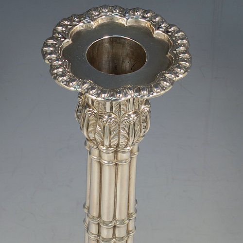 An Antique Georgian Sterling Silver pair of table candlesticks, in a Neoclassical style having square bases with bead borders, hand-chased floral swags and male head motifs, the columns in a bound palm-tree style with frond capitals, and removable nozzles. Made by John Cox of London in 1771. The dimensions of these fine antique silver candlesticks are height 32 cms (12.5 inches), bases 12.5 cms (5 inches) square. Please note that these candlesticks are crested.