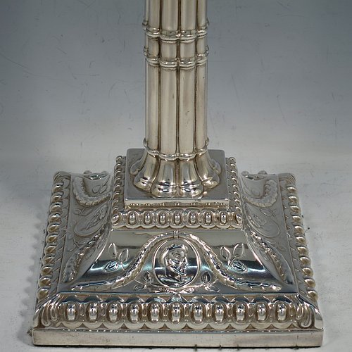 An Antique Georgian Sterling Silver pair of table candlesticks, in a Neoclassical style having square bases with bead borders, hand-chased floral swags and male head motifs, the columns in a bound palm-tree style with frond capitals, and removable nozzles. Made by John Cox of London in 1771. The dimensions of these fine antique silver candlesticks are height 32 cms (12.5 inches), bases 12.5 cms (5 inches) square. Please note that these candlesticks are crested.