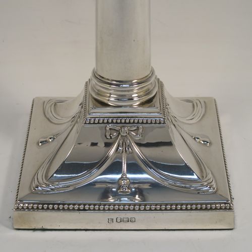 A very pretty pair of Antique Sterling Silver table candlesticks, in a Neoclassical Corinthian style having square bases with hand-chased swags, ribbons and bows, and bead-edged borders, with original removable nozzles. This beautiful pair of antique silver candlesticks were made by Thomas Bradbury and Sons of Sheffield in 1918. The dimensions of this fine hand-made pair antique silver candlesticks are height 31 cms (12.25 inches), and their bases are 12.5 cms (5 inches) square.