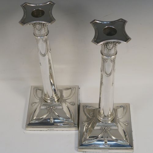 A very pretty pair of Antique Sterling Silver table candlesticks, in a Neoclassical Corinthian style having square bases with hand-chased swags, ribbons and bows, and bead-edged borders, with original removable nozzles. This beautiful pair of antique silver candlesticks were made by Thomas Bradbury and Sons of Sheffield in 1918. The dimensions of this fine hand-made pair antique silver candlesticks are height 31 cms (12.25 inches), and their bases are 12.5 cms (5 inches) square.