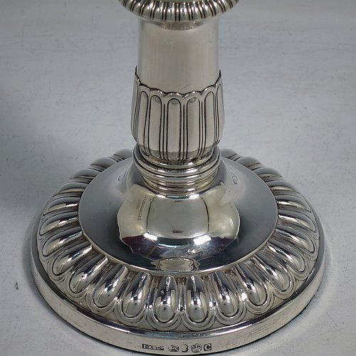 An Antique Georgian Sterling Silver handsome pair of Regency style candlesticks, having round baluster bodies, with removable nozzles, and sitting on round bases, all with hand-chased melon-fluted decoration and applied gadroon borders. Made by John Roberts & Co., of Sheffield in 1811. The dimensions of these fine hand-made antique silver table candlesticks are height 19.5 cms (7.75 inches), and the bases are 12 cms (4.75 inches) in diameter. Please note that these candlesticks are crested with the Latin motto Ne Vile Fano for the Earls of Westmorland.