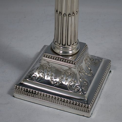 An Antique Sterling Silver pair of candlesticks, in a Neoclassical Corinthian style with square bases and round straight-sided fluted columns, having applied beaded borders, with hand-chased swags and scrolls, and removable nozzles. Made by James Dixon of Sheffield in 1912. The dimensions of this fine pair of hand-made antique silver candlesticks are height 22 cms (8.75 inches), and the bases are 9.5 cms (3.75 inches) square.