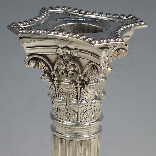 An Antique Sterling Silver pair of candlesticks, in a Neoclassical Corinthian style with square bases and round straight-sided fluted columns, having applied beaded borders, with hand-chased swags and scrolls, and removable nozzles. Made by James Dixon of Sheffield in 1912. The dimensions of this fine pair of hand-made antique silver candlesticks are height 22 cms (8.75 inches), and the bases are 9.5 cms (3.75 inches) square.
