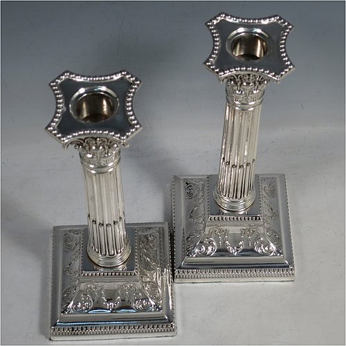 An Antique Sterling Silver pair of candlesticks, in a Neoclassical Corinthian style with square bases and round straight-sided fluted columns, having applied beaded borders, with hand-chased swags and scrolls, and removable nozzles. Made by James Dixon of Sheffield in 1912. The dimensions of this fine pair of hand-made antique silver candlesticks are height 22 cms (8.75 inches), and the bases are 9.5 cms (3.75 inches) square.