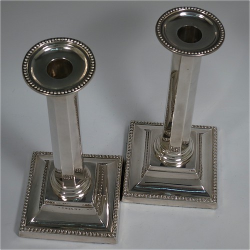 An Antique Victorian Sterling Silver pair of very pretty table candlesticks with bead-edged borders, having square bases with straight hexagonal panelled columns, with plain round capitals and removable nozzles. Made by Martin Hall and Co., of Sheffield in 1897. The dimensions of this fine hand-made pair of antique silver candlesticks are height 23 cms (9 inches), and 11 cms (4.3 inches) square at the base.