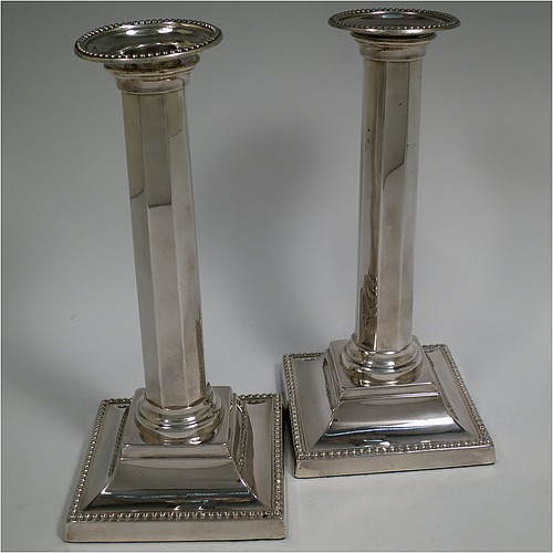 An Antique Victorian Sterling Silver pair of very pretty table candlesticks with bead-edged borders, having square bases with straight hexagonal panelled columns, with plain round capitals and removable nozzles. Made by Martin Hall and Co., of Sheffield in 1897. The dimensions of this fine hand-made pair of antique silver candlesticks are height 23 cms (9 inches), and 11 cms (4.3 inches) square at the base.