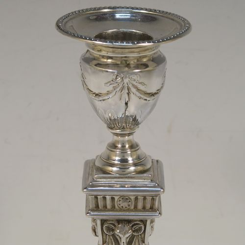 A very pretty pair of Antique Victorian Sterling Silver Neoclassical style candlesticks, having bead-edged borders, with hand-chased rams heads, swags, ribbons, and tureens, with removable nozzles, and square bases. These beautiful antique silver candlesticks were made by William Hutton and Sons of London in 1895. The dimensions of this fine hand-made pair of antique silver candlesticks are height 20 cms (8 inches), and the bases are 9 cms (3.5 inches) square.