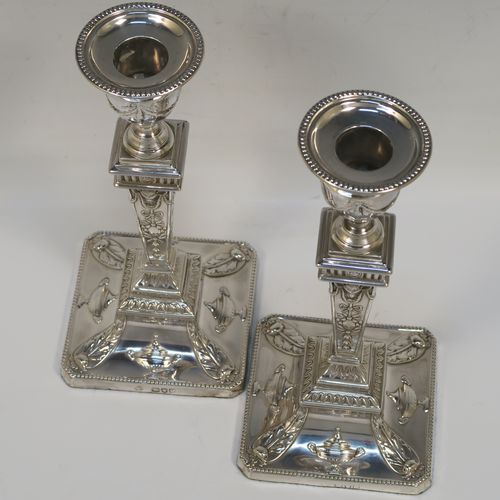 A very pretty pair of Antique Victorian Sterling Silver Neoclassical style candlesticks, having bead-edged borders, with hand-chased rams heads, swags, ribbons, and tureens, with removable nozzles, and square bases. These beautiful antique silver candlesticks were made by William Hutton and Sons of London in 1895. The dimensions of this fine hand-made pair of antique silver candlesticks are height 20 cms (8 inches), and the bases are 9 cms (3.5 inches) square.