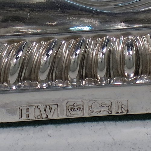 An Antique Edwardian Sterling Silver pair of candlesticks, in a Neoclassical Corinthian style with square bases and round straight-sided columns, having applied gadroon borders, hand-chased bows with swag decoration, and removable nozzles. Made by Henry Wilkinson of Sheffield in 1902. The dimensions of this fine pair of hand-made antique silver candlesticks are height 19 cms (7.5 inches), and the bases are 10 cms (4 inches) square.