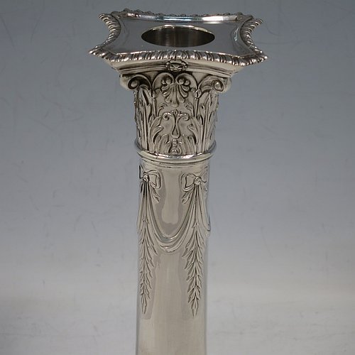 An Antique Edwardian Sterling Silver pair of candlesticks, in a Neoclassical Corinthian style with square bases and round straight-sided columns, having applied gadroon borders, hand-chased bows with swag decoration, and removable nozzles. Made by Henry Wilkinson of Sheffield in 1902. The dimensions of this fine pair of hand-made antique silver candlesticks are height 19 cms (7.5 inches), and the bases are 10 cms (4 inches) square.