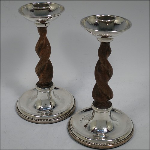 A very unusual and pretty Sterling Silver pair of Arts and Crafts candlesticks, having round bases with a hand-hammered finish and applied rope-twist lower borders, with hand-carved wooden swirl columns, and round capitals with deep drip pans. Made by A. E. Jones of Birmingham in 1920. The dimensions of these fine hand-made Arts and Crafts silver candlesticks are height 17 cms (6.75 inches), and diameter at base 10 cms (4 inches).   