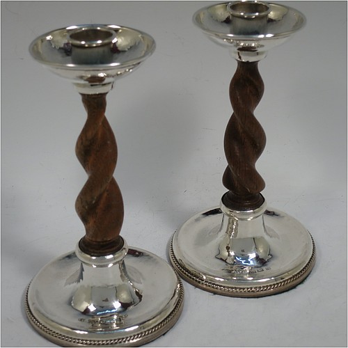A very unusual and pretty Sterling Silver pair of Arts and Crafts candlesticks, having round bases with a hand-hammered finish and applied rope-twist lower borders, with hand-carved wooden swirl columns, and round capitals with deep drip pans. Made by A. E. Jones of Birmingham in 1920. The dimensions of these fine hand-made Arts and Crafts silver candlesticks are height 17 cms (6.75 inches), and diameter at base 10 cms (4 inches).