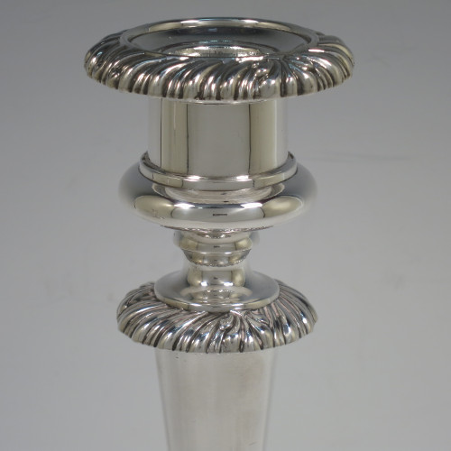 A very handsome pair of Antique Georgian Regency Sterling Silver candlesticks, having hand-chased fluted decoration and applied gadroon and shell borders, with their original removable nozzles, and round pedestal bases. Made by Matthew Boulton of Birmingham in 1817. The dimensions of this fine hand-made pair of antique silver candlesticks are height 23.5 cms (9.25 inches), and diameter of bases 12 cms (4.75 inches).