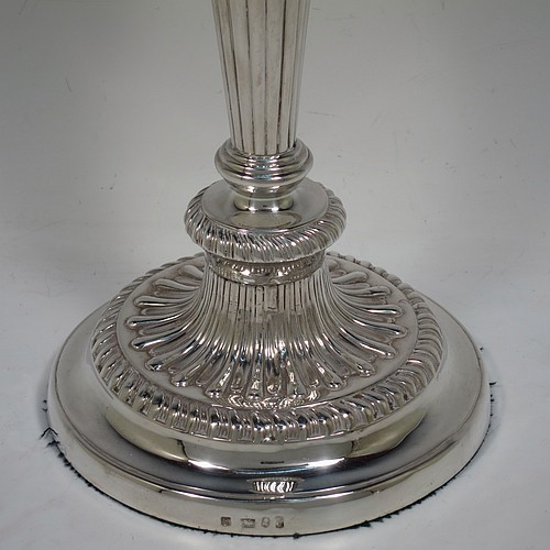 A very handsome pair of Antique Georgian Sterling Silver candlesticks, having hand-chased fluted decoration and applied gadroon borders, with their original removable nozzles, and round pedestal bases. Made by John and Thomas Settle of Sheffield in 1826. The dimensions of this fine hand-made pair of antique silver candlesticks are height 28 cms (11 inches), and diameter of bases 14 cms (5.5 inches).
