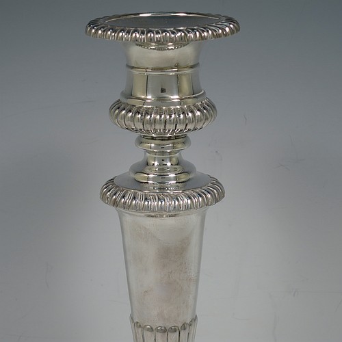 A very handsome pair of Antique Georgian Sterling Silver candlesticks, having hand-chased fluted decoration and applied gadroon borders, with their original removable nozzles, and round pedestal bases. Made by John and Thomas Settle of Sheffield in 1826. The dimensions of this fine hand-made pair of antique silver candlesticks are height 28 cms (11 inches), and diameter of bases 14 cms (5.5 inches).