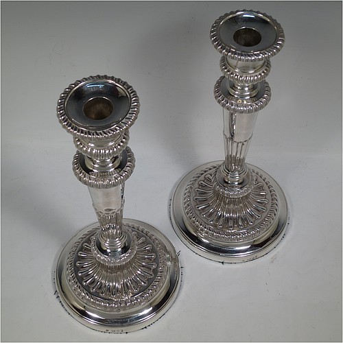 A very handsome pair of Antique Georgian Sterling Silver candlesticks, having hand-chased fluted decoration and applied gadroon borders, with their original removable nozzles, and round pedestal bases. Made by John and Thomas Settle of Sheffield in 1826. The dimensions of this fine hand-made pair of antique silver candlesticks are height 28 cms (11 inches), and diameter of bases 14 cms (5.5 inches).