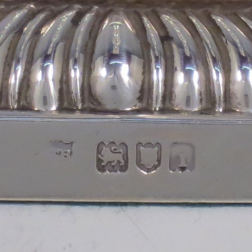 An Antique Edwardian Sterling Silver handsome set of four candlesticks in a George I style, having round baluster bodies, with removable square nozzles, and sitting on square bases, all with hand-chased fluted decoration and applied gadroon borders. Made by Thomas Bradbury of London in 1904. The dimensions of these fine hand-made antique silver table candlesticks are height 23.5 cms (9.25 inches), and the bases are 11 cms (4.3 inches) square.