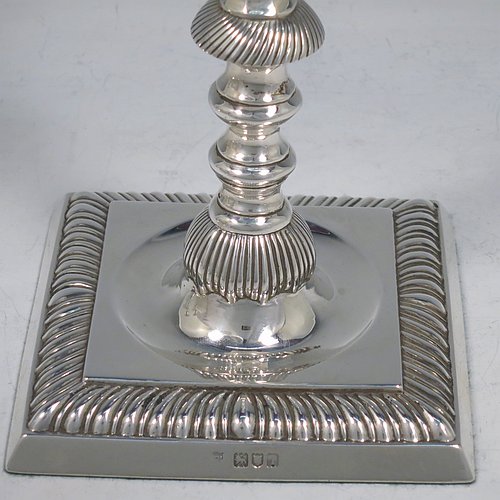 An Antique Edwardian Sterling Silver handsome set of four candlesticks in a George I style, having round baluster bodies, with removable square nozzles, and sitting on square bases, all with hand-chased fluted decoration and applied gadroon borders. Made by Thomas Bradbury of London in 1904. The dimensions of these fine hand-made antique silver table candlesticks are height 23.5 cms (9.25 inches), and the bases are 11 cms (4.3 inches) square.