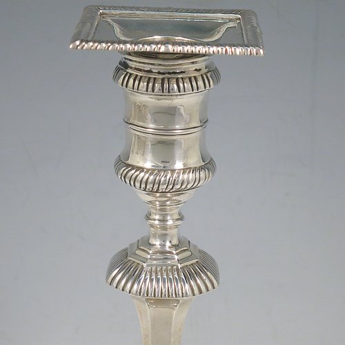 An Antique Edwardian Sterling Silver handsome set of four candlesticks in a George I style, having round baluster bodies, with removable square nozzles, and sitting on square bases, all with hand-chased fluted decoration and applied gadroon borders. Made by Thomas Bradbury of London in 1904. The dimensions of these fine hand-made antique silver table candlesticks are height 23.5 cms (9.25 inches), and the bases are 11 cms (4.3 inches) square.