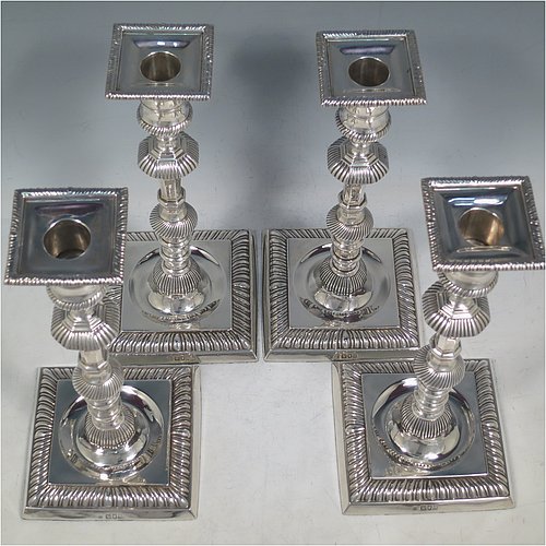 An Antique Edwardian Sterling Silver handsome set of four candlesticks in a George I style, having round baluster bodies, with removable square nozzles, and sitting on square bases, all with hand-chased fluted decoration and applied gadroon borders. Made by Thomas Bradbury of London in 1904. The dimensions of these fine hand-made antique silver table candlesticks are height 23.5 cms (9.25 inches), and the bases are 11 cms (4.3 inches) square.