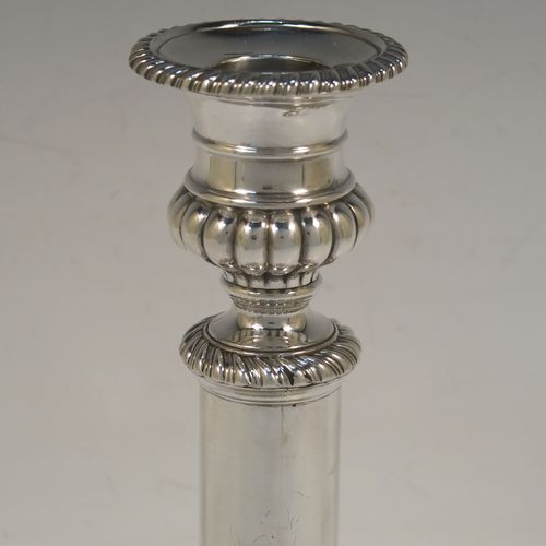 A very handsome Antique Georgian Sterling Silver handsome pair of Regency style candlesticks, having round baluster bodies, with removable nozzles, and sitting on round bases, all with hand-chased melon-fluted decoration and applied gadroon borders. These elegant antique silver candlesticks were made by John and Thomas Settle of Sheffield in 1819. The dimensions of these fine hand-made antique silver table candlesticks are height 21 cms (8.25 inches), and the bases are 12.5 cms (5 inches) in diameter.