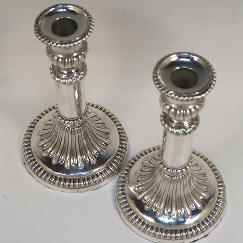 A very handsome Antique Georgian Sterling Silver handsome pair of Regency style candlesticks, having round baluster bodies, with removable nozzles, and sitting on round bases, all with hand-chased melon-fluted decoration and applied gadroon borders. These elegant antique silver candlesticks were made by John and Thomas Settle of Sheffield in 1819. The dimensions of these fine hand-made antique silver table candlesticks are height 21 cms (8.25 inches), and the bases are 12.5 cms (5 inches) in diameter.