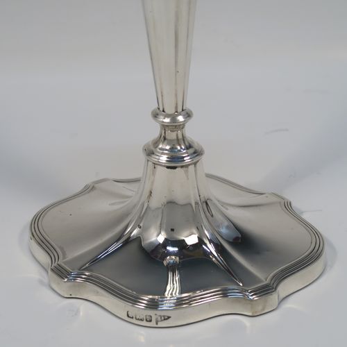A very handsome pair of Antique Edwardian Sterling Silver candlesticks, having Neoclassical style oval shaped bodies, with hand-chased fluted decoration, reeded borders, and removable nozzles. These elegant silver candlesticks were made by Walker and Hall of Sheffield in 1909. The dimensions of this fine hand-made pair of antique silver table candlesticks are height 24 cms (9.5 inches), length at base 13 cms (5 inches), and width at base 10 cms (4 inches).   