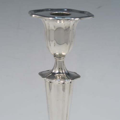A very handsome pair of Antique Edwardian Sterling Silver candlesticks, having Neoclassical style oval shaped bodies, with hand-chased fluted decoration, reeded borders, and removable nozzles. These elegant silver candlesticks were made by Walker and Hall of Sheffield in 1909. The dimensions of this fine hand-made pair of antique silver table candlesticks are height 24 cms (9.5 inches), length at base 13 cms (5 inches), and width at base 10 cms (4 inches).   