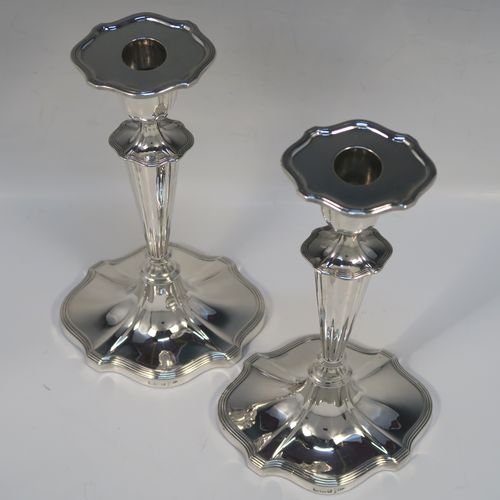 A very handsome pair of Antique Edwardian Sterling Silver candlesticks, having Neoclassical style oval shaped bodies, with hand-chased fluted decoration, reeded borders, and removable nozzles. These elegant silver candlesticks were made by Walker and Hall of Sheffield in 1909. The dimensions of this fine hand-made pair of antique silver table candlesticks are height 24 cms (9.5 inches), length at base 13 cms (5 inches), and width at base 10 cms (4 inches).   