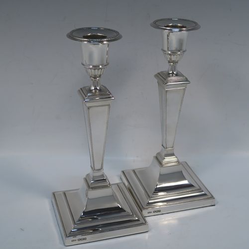 A very handsome Antique Sterling silver pair of table candlesticks, in a Neoclassical style, having square cross-section bodies with applied bead-edged borders, tapering columns, and removable nozzles. These elegant silver candlesticks were made by Thomas Scott of Sheffield in 1912. The dimensions of these fine hand-made antique silver candlesticks are height 20.5 cms (8 inches), and 9 cms (3.5 inches) square at bases.   