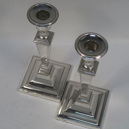 A very handsome Antique Sterling silver pair of table candlesticks, in a Neoclassical style, having square cross-section bodies with applied bead-edged borders, tapering columns, and removable nozzles. These elegant silver candlesticks were made by Thomas Scott of Sheffield in 1912. The dimensions of these fine hand-made antique silver candlesticks are height 20.5 cms (8 inches), and 9 cms (3.5 inches) square at bases.