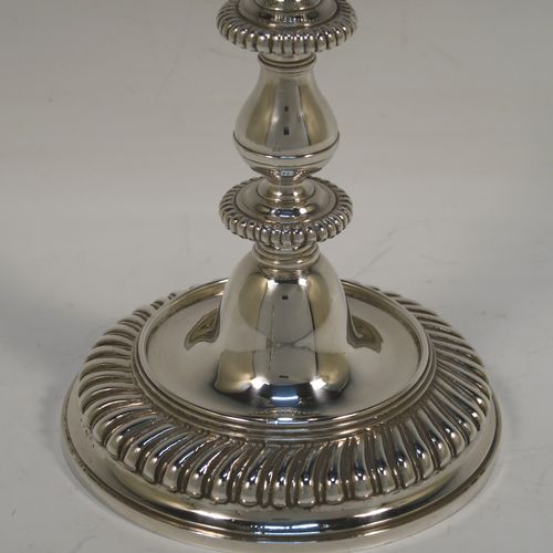 A very handsome pair of cast Britannia standard Silver candlesticks in an early Queen Ann style, having round baluster bodies with applied and hand-chased fluted borders. These elegant cast silver candlesticks were made by Wakely and Wheeler of London in 1967. The dimensions of this fine pair of hand-made cast sterling silver table candlesticks are height 17 cms (6.75 inches), the bases are 11 cms (4.25 inches) in diameter, and the total weight is 871g (28 troy ounces).